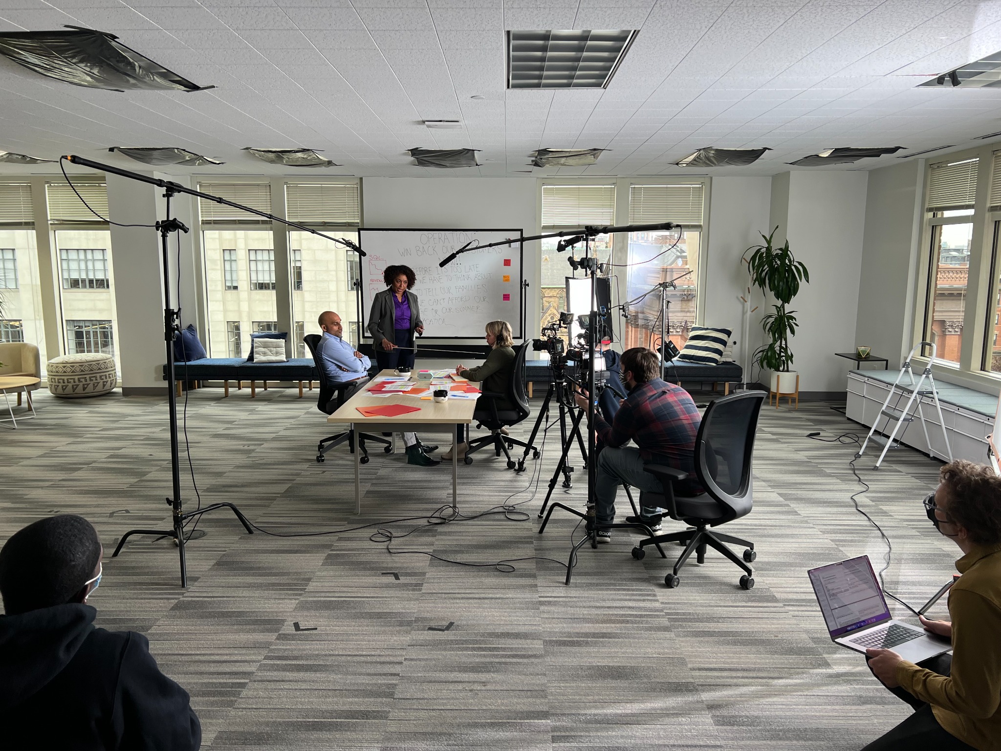 Actors and camera crew filming a conference-room scene